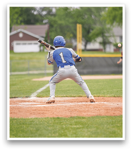 A baseball player in a blue and white uniform is swinging a bat at a ball. Description generated by AI