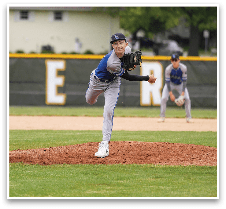 A baseball player in a blue shirt and grey pants is pitching a ball. Description generated by AI