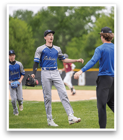 A baseball player wearing a blue shirt and grey pants with a catcher's mitt on his hand. Description generated by AI