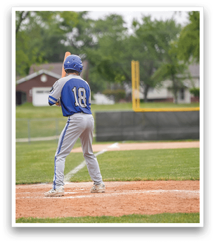 A baseball player in a blue and grey uniform is holding a bat and getting ready to swing. Description generated by AI