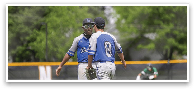 Two baseball players wearing blue and white uniforms talking to each other. Description generated by AI