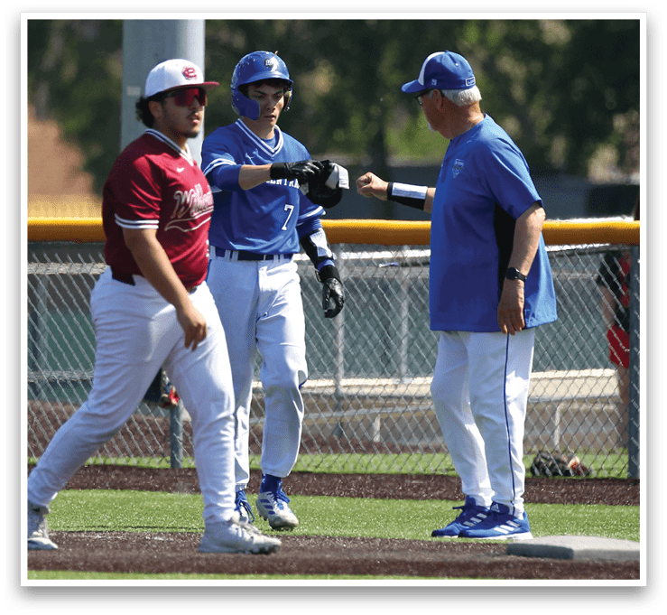 A baseball game is taking place with a man in a blue shirt and white pants talking to a man in a red shirt. Description generated by AI