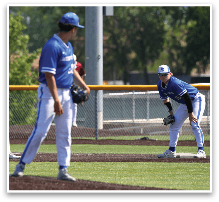 A baseball player in a blue shirt and white pants is standing on the field. Description generated by AI