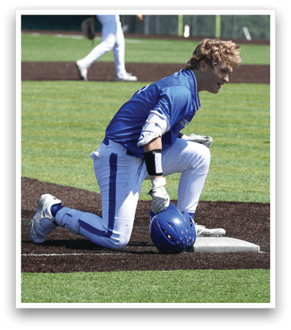 A baseball player kneeling on the ground with a blue helmet and white pants. Description generated by AI