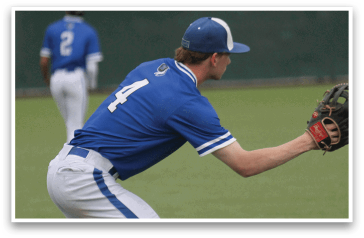 A baseball player wearing a blue and white uniform is bending over to catch a ball. Description generated by AI