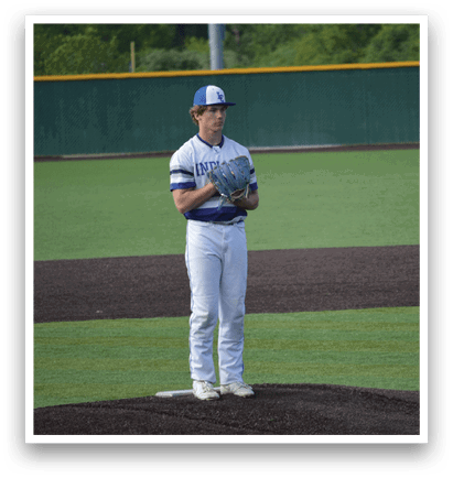 A baseball player in a blue and white uniform stands on a pitcher's mound. Description generated by AI