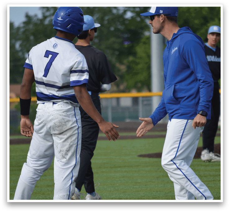 Two men wearing blue and white shirts are shaking hands. Description generated by AI