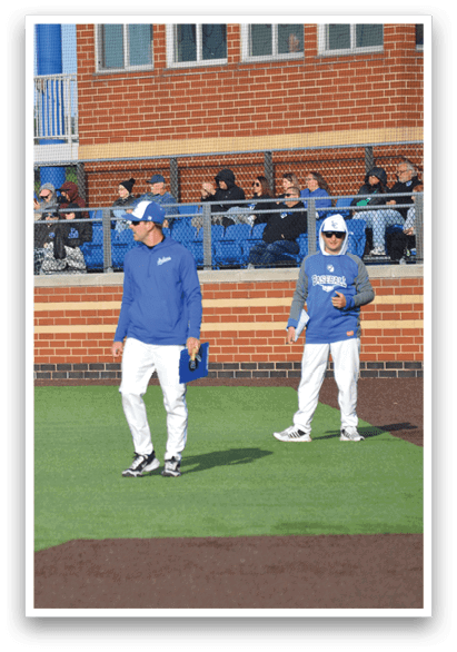 Two baseball players standing on a field. Description generated by AI