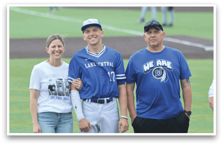 A man and woman standing on a baseball field with a man in a blue shirt and hat. Description generated by AI