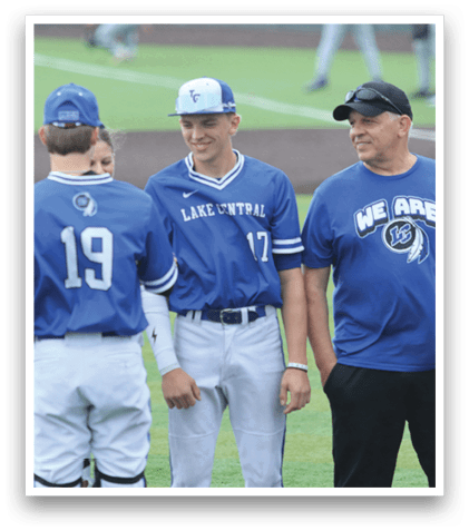 Three men wearing blue shirts and white pants standing on a baseball field. Description generated by AI