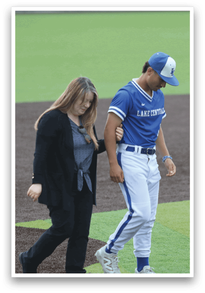 A man wearing a blue shirt and white pants walks on a field. Description generated by AI