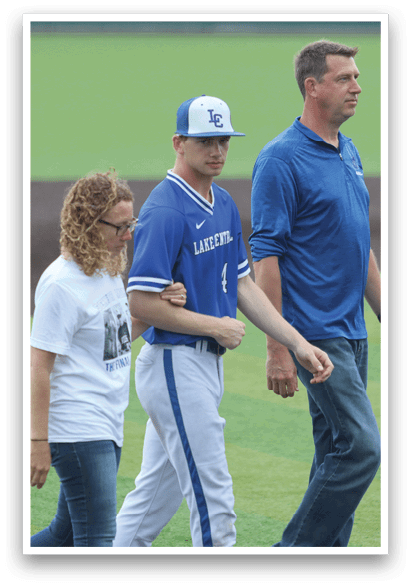 A man wearing a blue shirt and white pants walks with two women. Description generated by AI