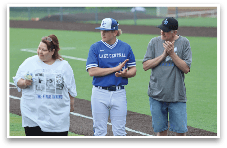 A man wearing a blue shirt and white pants stands on a baseball field. Description generated by AI