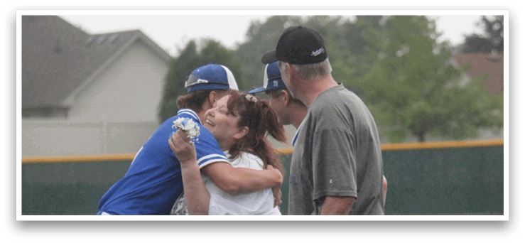A group of people hugging on a baseball field. Description generated by AI