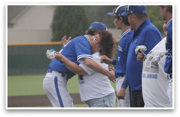 A group of people hugging on a baseball field. Description generated by AI
