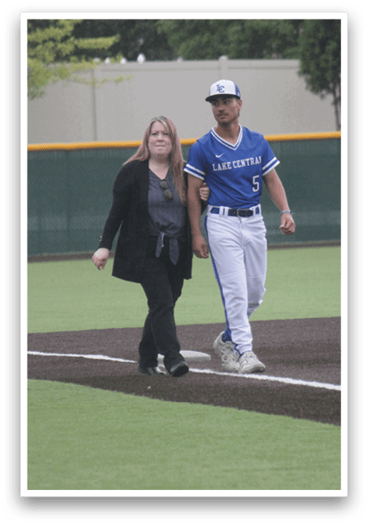 A man and a woman walking on a baseball field. Description generated by AI
