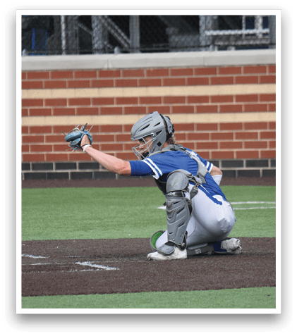 A baseball player in a blue and white uniform is kneeling on the ground. Description generated by AI