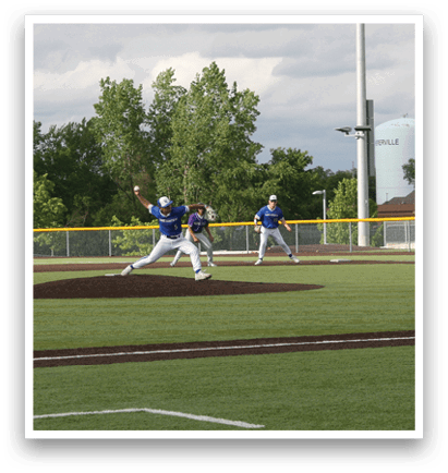 A baseball player in a blue shirt and white pants is pitching a ball. Description generated by AI