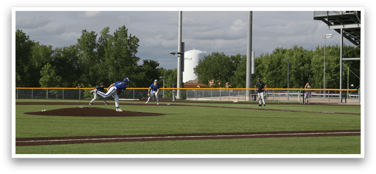 A baseball player in a blue shirt and white pants is pitching a ball. Description generated by AI