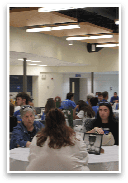 A group of people are sitting around a table in a room. Description generated by AI