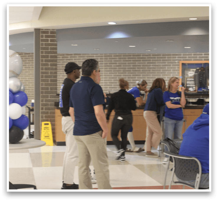 A group of people standing in a room. Description generated by AI