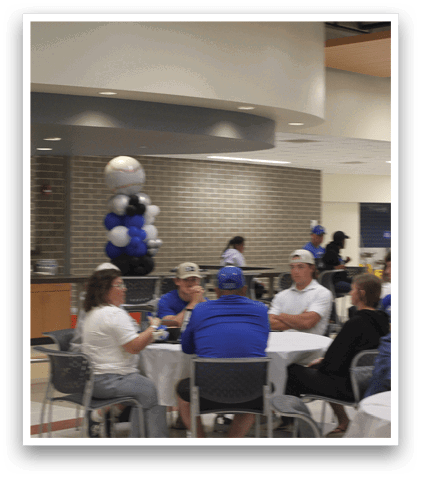 A group of people are sitting around a table with a blue tablecloth. Description generated by AI
