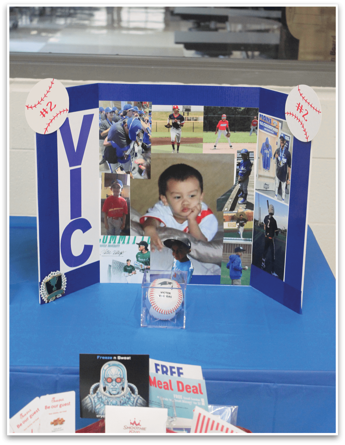 A blue table with a display of photos and a baseball. Description generated by AI