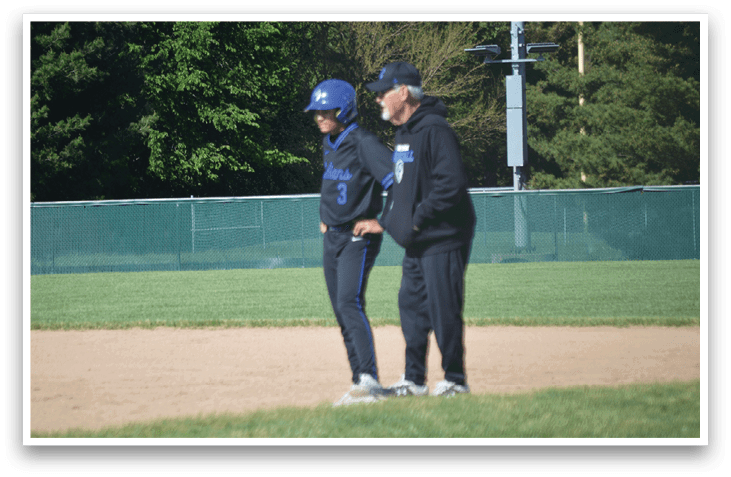 Two people standing on a baseball field. Description generated by AI