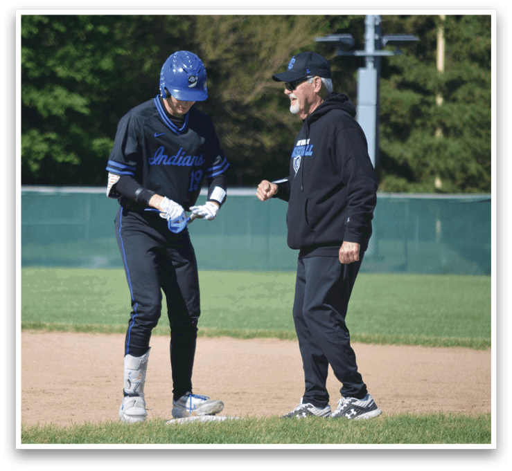 A baseball player wearing a blue and black uniform is talking to a coach. Description generated by AI