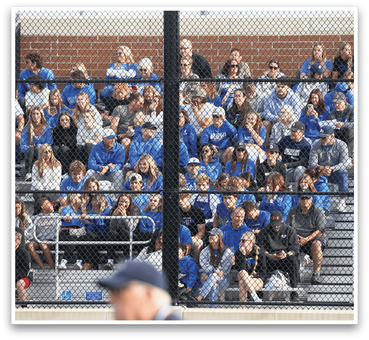 A crowd of people in blue shirts are sitting in the bleachers. Description generated by AI
