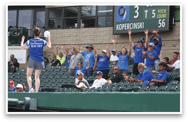 A woman in a blue shirt is standing on a baseball field. Description generated by AI