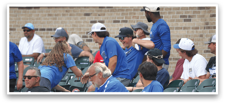 A group of people wearing blue shirts are sitting in the stands. Description generated by AI