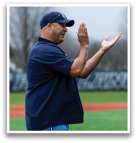 A man wearing a blue shirt and blue pants is standing on a baseball field, clapping his hands. AI generated content