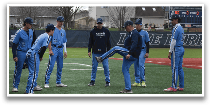 A group of young men wearing blue uniforms are standing on a baseball field. One of the players is kicking a ball, while the others watch and prepare for the next play. AI generated content