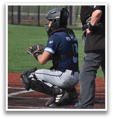 A baseball catcher is squatting on the field, wearing a helmet and a blue shirt. AI generated content