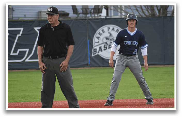 A baseball player in a blue and gray uniform stands on a field, waiting for the ball. A man in a black shirt and gray pants, likely an umpire, stands nearby, watching the game. AI generated content