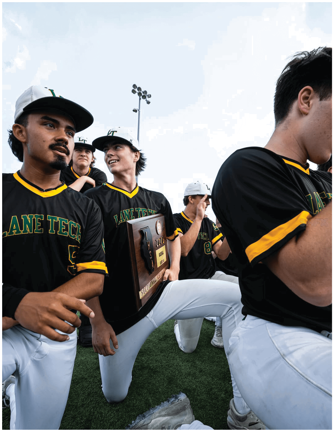 A baseball player with a black shirt and yellow letters on it. Description generated by AI