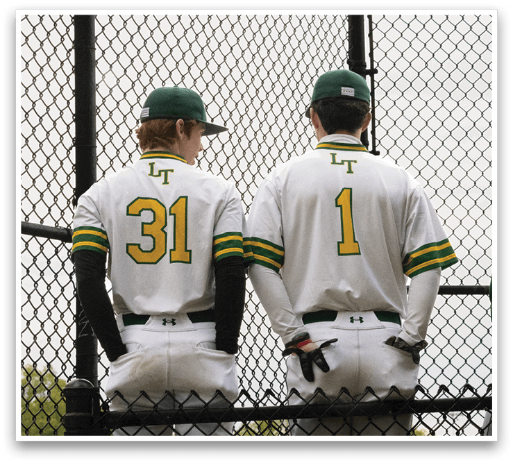 Two baseball players wearing white uniforms with green and yellow stripes. Description generated by AI