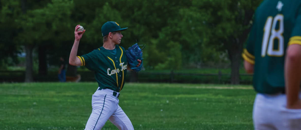A baseball player in a green and yellow uniform is pitching a ball. Description generated by AI