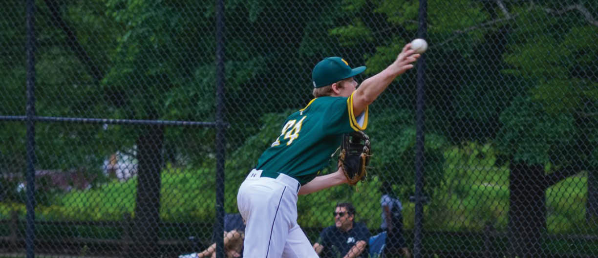 A baseball player wearing a green and yellow shirt and white pants is throwing a ball. Description generated by AI