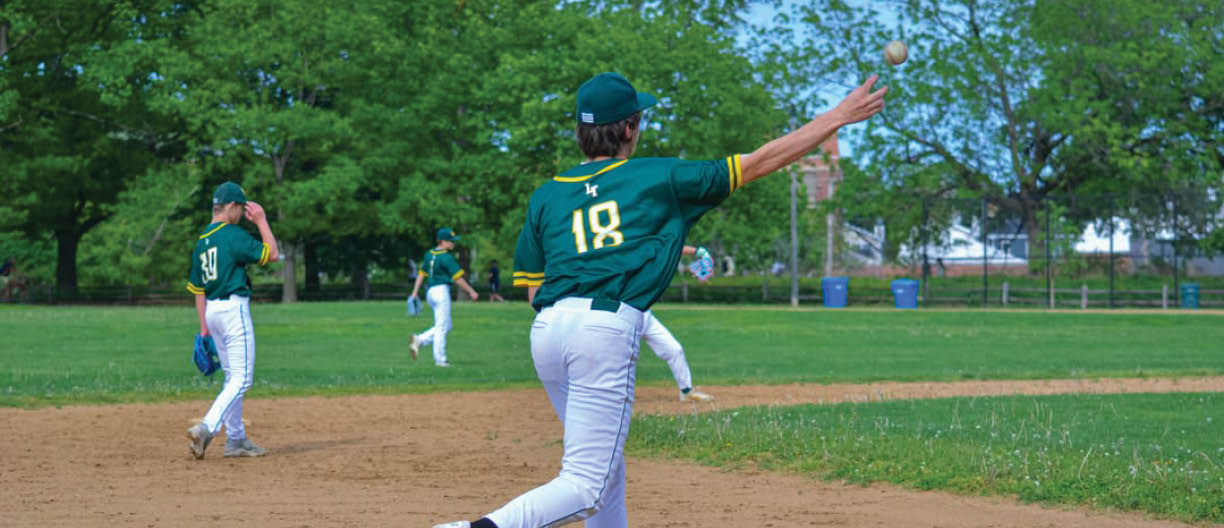 A baseball player wearing a green and white uniform is throwing a ball. Description generated by AI