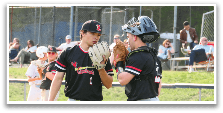 Two baseball players wearing black shirts and grey pants are talking to each other on a field. One player is holding a baseball glove. AI generated content