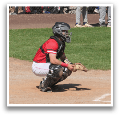 A baseball player is crouched down in the dirt, wearing a catcher's mitt and ready to catch the ball. AI generated content