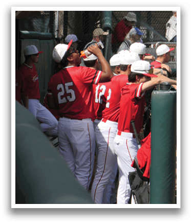 A group of baseball players wearing red and white uniforms are standing around a batting cage. AI generated content