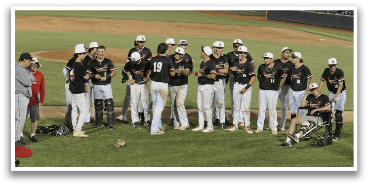 Baseball players on a field, some standing and some sitting, wearing black and red uniforms. AI generated content