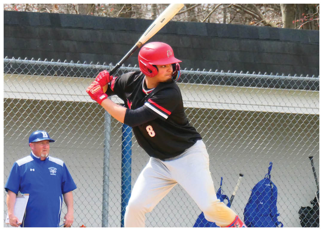 A baseball player in a red helmet and black shirt is swinging a bat. Description generated by AI
