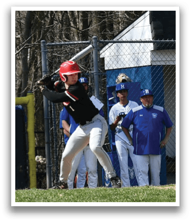 A baseball player in a black shirt and red helmet is swinging a bat. Description generated by AI