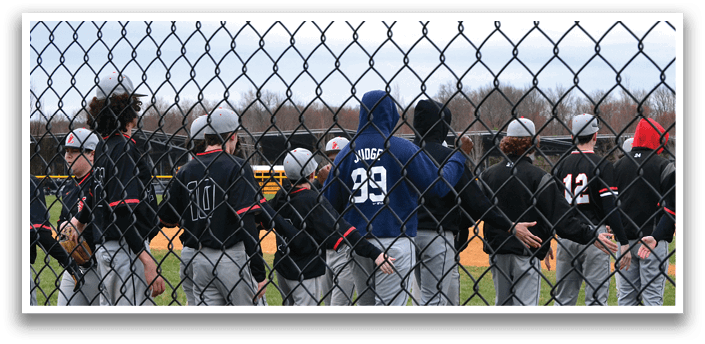 A group of young men standing in front of a fence. Description generated by AI