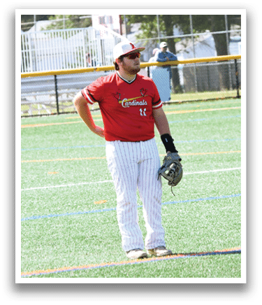 A baseball player wearing a red shirt and white pants stands on a field. Description generated by AI