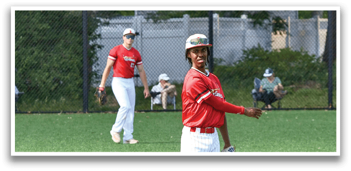 A baseball player in a red shirt and white pants is holding a baseball glove. Description generated by AI